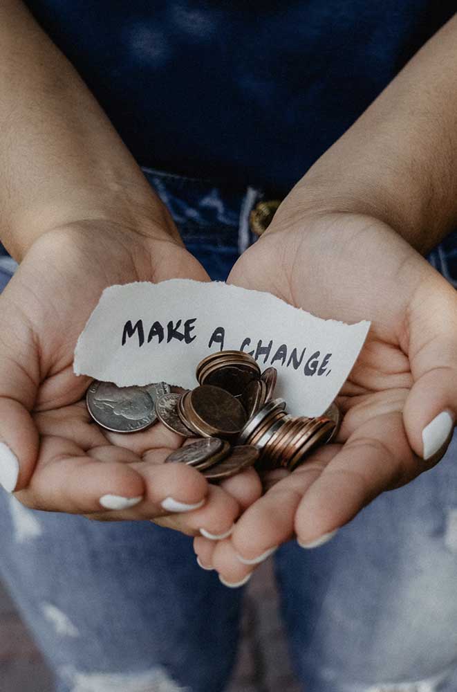 Hands holding coins with sign 'Make a change'