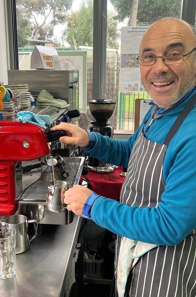 Smiling man making coffee with commercial coffee machine